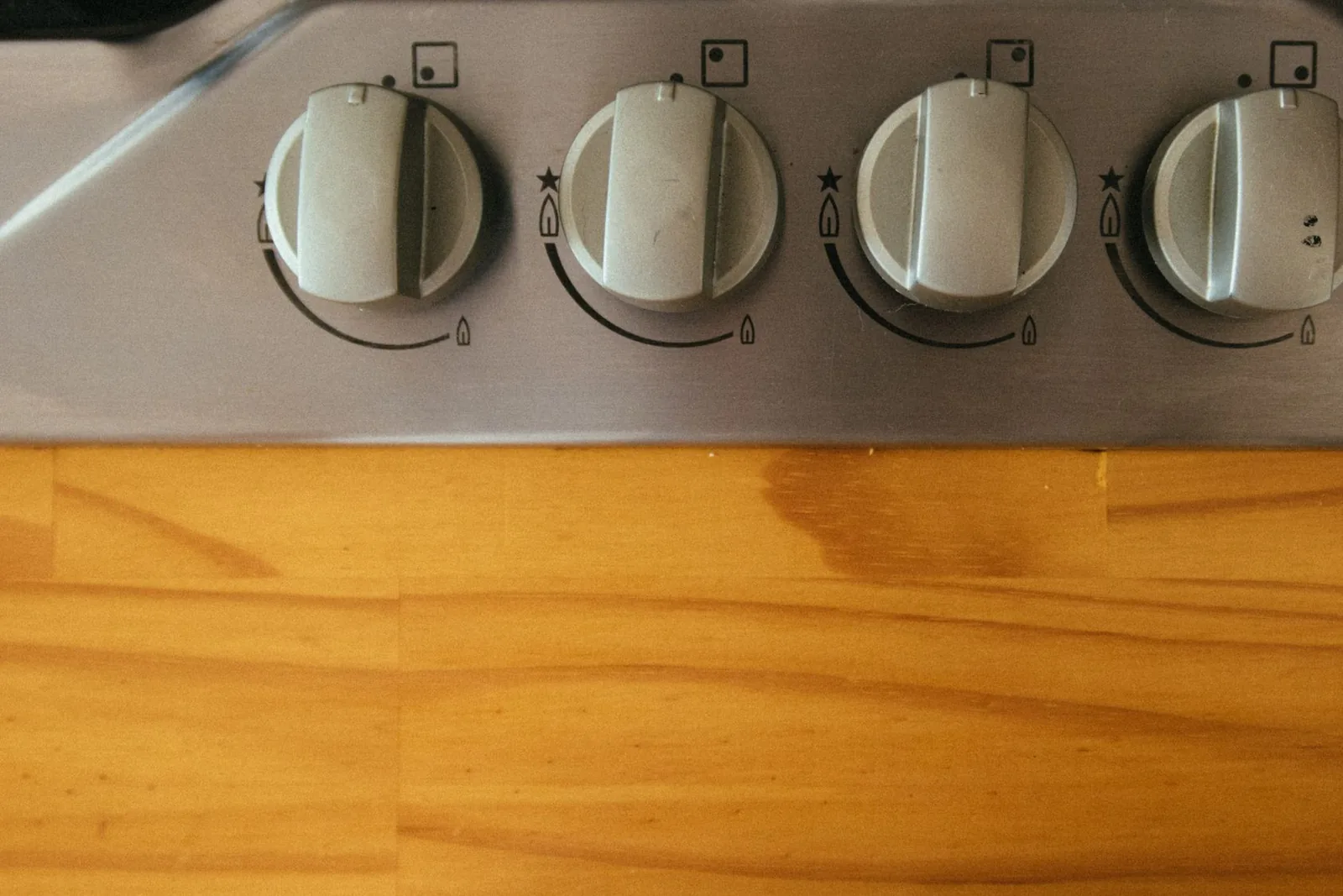 Mandos de una cocina de gas sobre una encimera de madera, un aparato de uso diario en casa