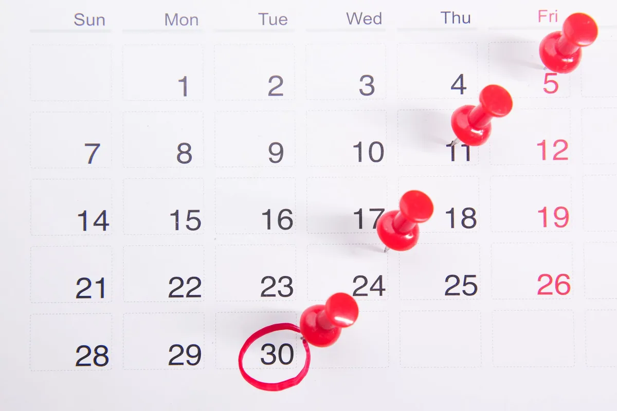 Calendario con chinchetas rojas y el día 30 rodeado con un círculo rojo