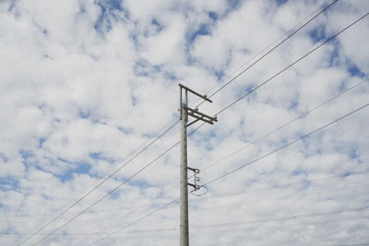 Poste de la luz con cables eléctricos contra un cielo con nubes