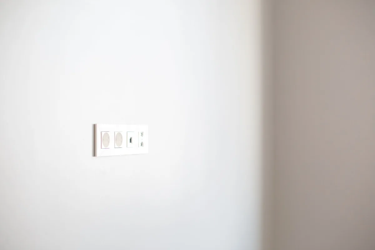 Pared blanca con un panel de tomas de corriente y una toma de datos