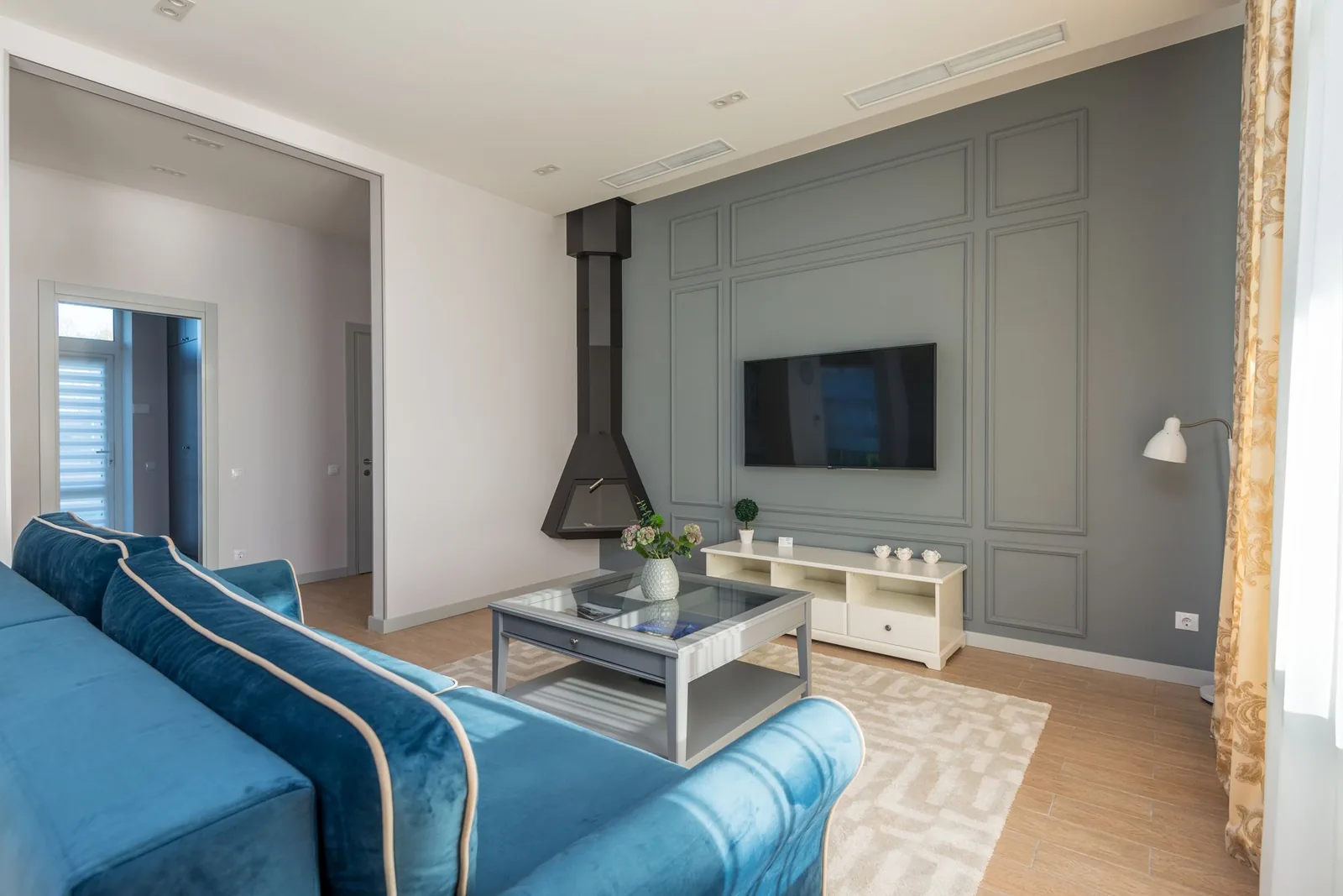 Televisor apagado en la pared de un salón, sobre un mueble bajo