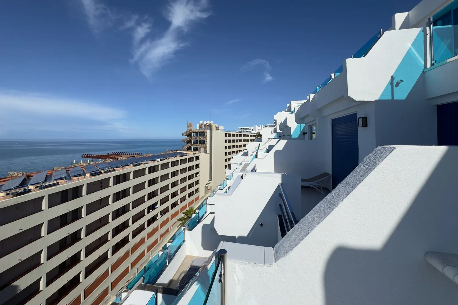 Apartamentos blancos de tejado plano con terrazas escalonadas y vistas al mar